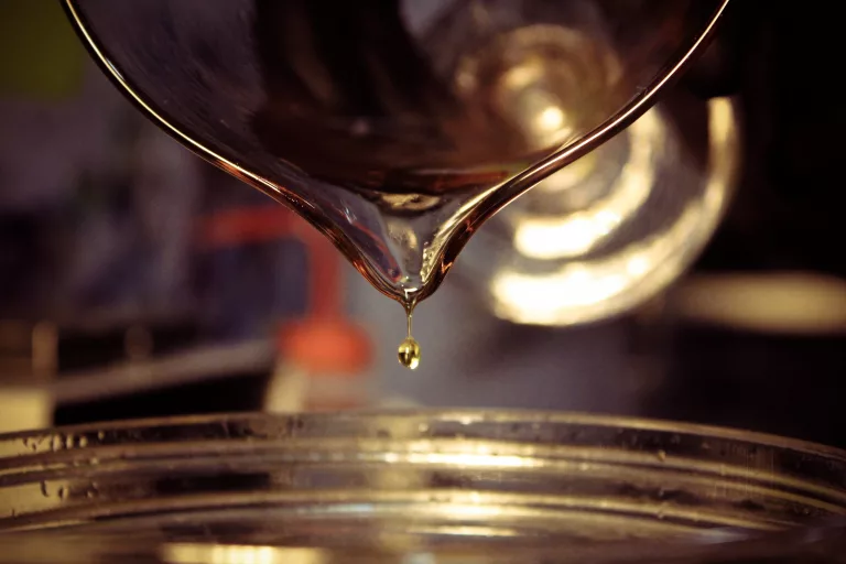 A beaker with liquid dropping out hair product ingredient.