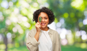 woman of color with black curly hair holding up a leaf
