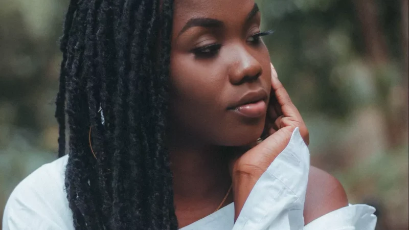 African American woman with locs. African American woman with locs in a white shirt.